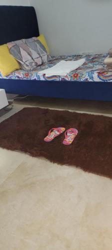 a pair of shoes on a rug next to a bed at Home Away Apartment in Abu Dhabi