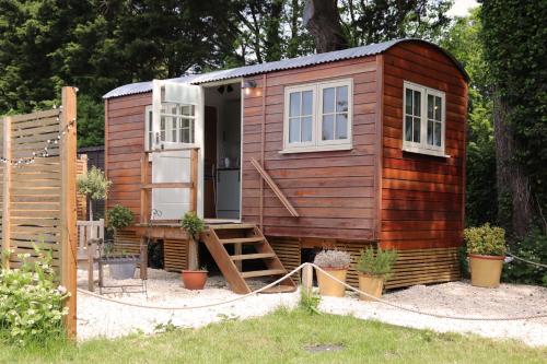 a wooden tiny house with a staircase in a yard at Cobo Cottage in Chichester