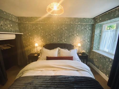 a bedroom with a bed with green walls and a chandelier at Sandford Mount in the Costwolds in Charlbury