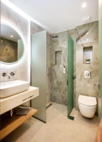 a bathroom with a sink and a toilet and a mirror at Vela Bianca Suites in Limenaria