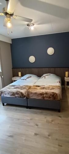 a bedroom with a large bed with a blue wall at 't Vakansie'uus in Serooskerke