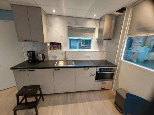 een keuken met witte kasten, een wastafel en een raam bij 't Vakansie'uus in Serooskerke