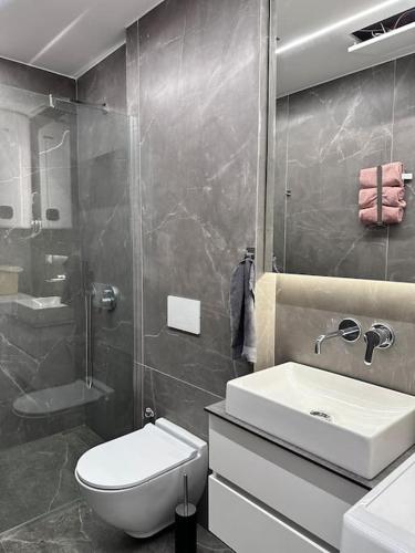 a bathroom with a toilet and a sink and a shower at Lumi Residence Apartment 2 in Sarandë