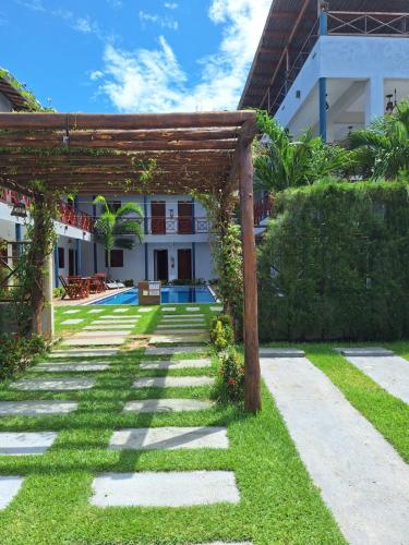 a garden with a wooden pergola in front of a building at Pousada Grand Fortim in Camocim