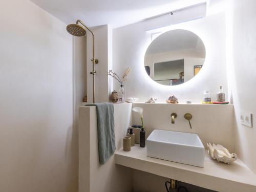 ein weißes Badezimmer mit einem Waschbecken und einem Spiegel in der Unterkunft CHEZ ADELA in Almoster