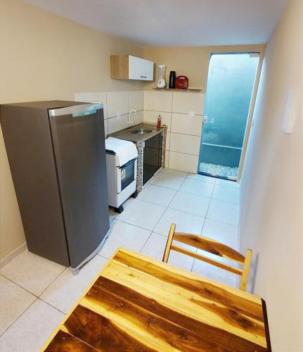uma cozinha com um frigorífico, uma mesa e uma cadeira em Abaré Slim Suítes em São Miguel dos Milagres