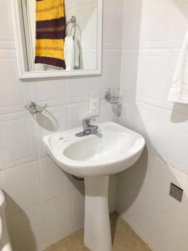 a white bathroom with a sink and a mirror at Casa Elim-Oaxaca in Teotitlán del Valle