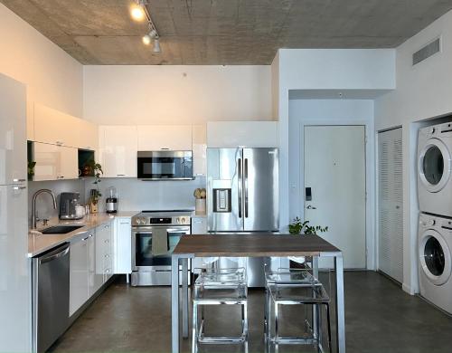 a kitchen with white cabinets and a table with stools at Zen Loft Downtown Miami in Miami