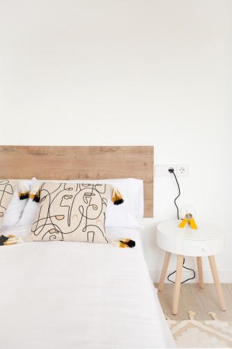 a white bedroom with a bed and a white table at Tu refugio junto al mar te espera in Elejalde