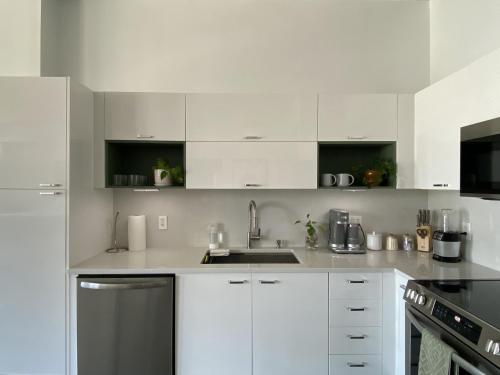 a white kitchen with white cabinets and a sink at Zen Loft Downtown Miami in Miami