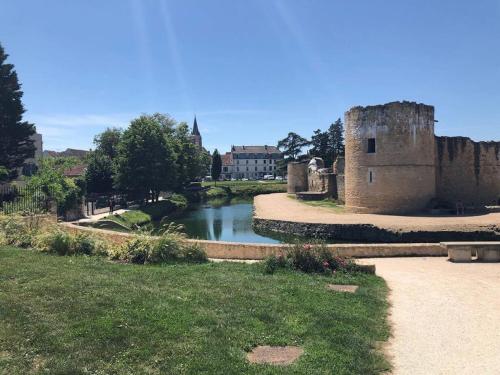 a river in front of a castle with a building at La Grenouillère in Brie-Comte-Robert