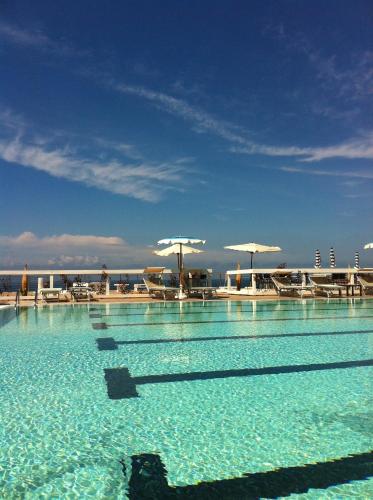 a swimming pool with blue water and chairs and umbrellas at La Rosa dei Venti Resort in Piombino