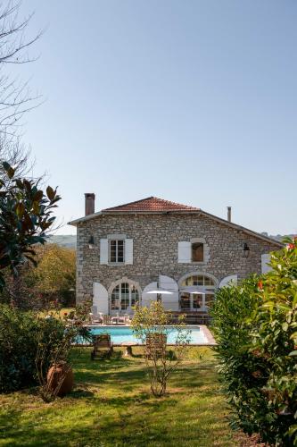 - une vue extérieure sur une maison en pierre avec une piscine dans l'établissement Domaine L'Ermitage 5 * au coeur des terres basquo-landaises, à Hastingues