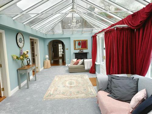 a living room with a glass ceiling and red curtains at Bushmount Lodge in Clonakilty
