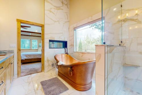 La salle de bains est pourvue d'une baignoire en cuivre et d'une fenêtre. dans l'établissement Luxury Mountain Retreat, à South Lake Tahoe