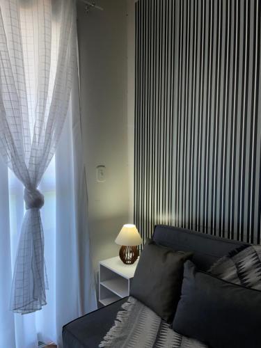 a bedroom with a blue couch and a window at FLAT frente Mar Green Diamond in Vila Velha