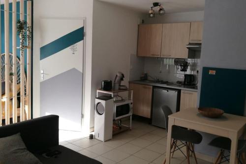 un salon avec une cuisine équipée d'une table et d'un comptoir dans l'établissement Studio Castelnau-le-Lez, à Castelnau-le-Lez