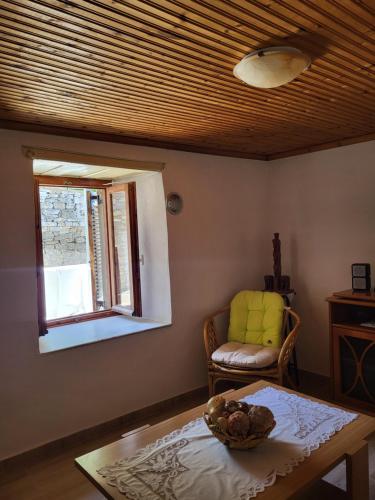 a living room with a table and a chair and a window at Παραδοσιακό σπίτι με θέα in Tríkeri