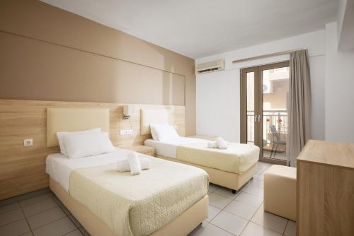 a hotel room with two beds and a balcony at Acropolis Apartments in Hersonissos