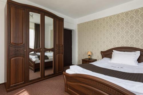 a bedroom with a bed and a large mirror at Popasul de Wis in Moieciu de Jos
