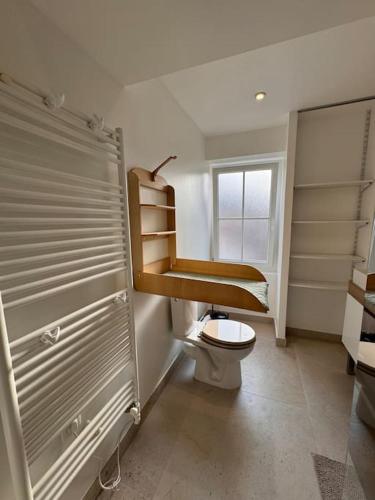 une salle de bain avec toilettes, lavabo et fenêtre dans l'établissement Maison Eole, à Bernières-sur-Mer