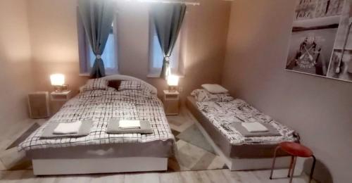 two twin beds in a room with a window at Dézsa-vü Vendégház in Sarud