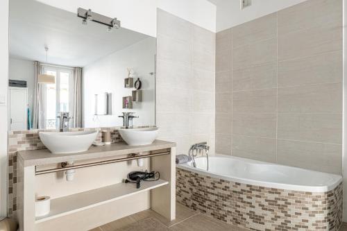 une salle de bain avec deux lavabos et une baignoire dans l'établissement 64m2 face Majestic - 50m palais & plages, à Cannes