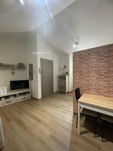 an empty living room with a table and a brick wall at Sophie Home - Comfort e Relax a pochi km da Nora in Pula