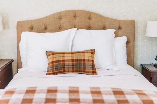 a bed with white pillows and a plaid pillow at The Greystone Inn in Lake Toxaway