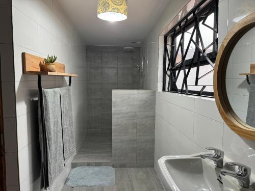 a bathroom with a tub and a sink and a mirror at Njombe Cozy House in Njombe