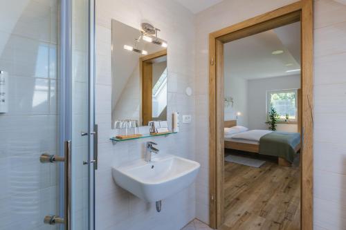 a bathroom with a sink and a shower and a bedroom at Domačija Log v Bohinju in Bohinjska Bistrica