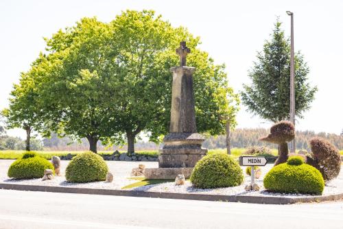 Hostal O'Cruceiro في O Pino : تمثال في حديقة به شجيرات وأشجار