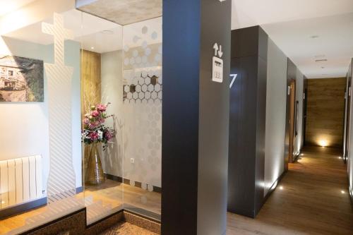 a hallway with a glass wall with a vase of flowers at Hostal O'Cruceiro in O Pino 