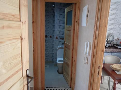 a bathroom with a toilet and a wooden door at OUALIDIA Catrass M in Oualidia
