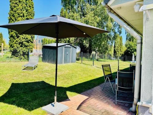 LütowにあるFerienwohnung Usedom Familie Stopp Apartment 23aのテーブルと椅子のあるレンガ造りのパティオに置かれた傘
