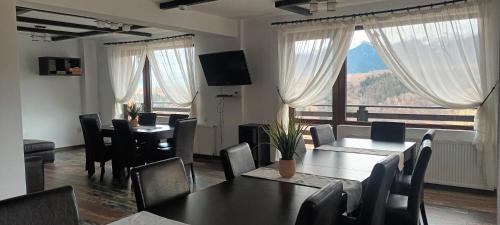 a dining room with tables and chairs and a large window at Popasul de Wis in Moieciu de Jos