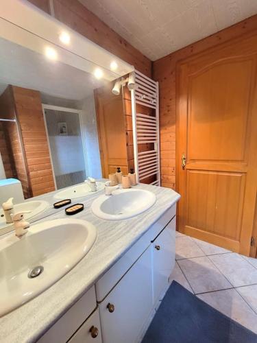 une salle de bain avec deux lavabos et un grand miroir dans l'établissement Chalet Goutelle, paisible en pleine nature, à Gérardmer