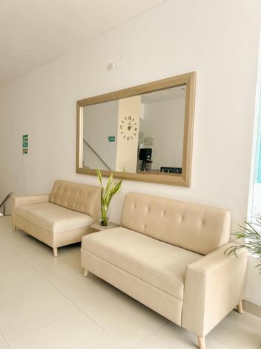 a living room with two couches and a mirror at Hotel Ginebra Sincelejo in Sincelejo