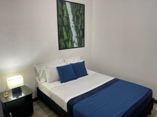 a bedroom with a bed with blue and white pillows at El solar casa hotel in Manizales
