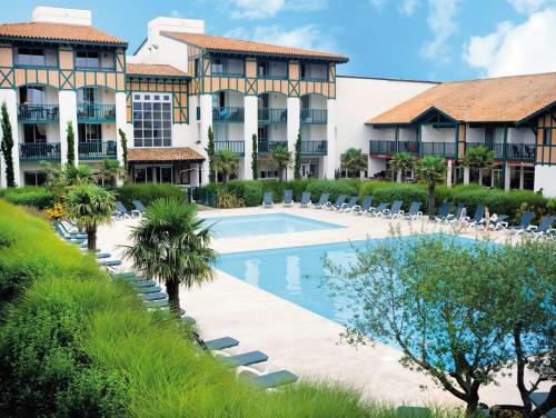 un complexe avec une piscine, des chaises et un bâtiment dans l'établissement Appartement LE DAOUN Dunes, Pins Océan et Golf, à Moliets-et-Maa