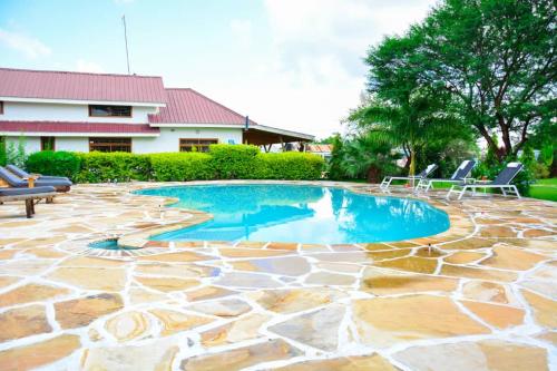 una piscina con sillas y un patio de piedra. en Heart of Africa Lodge, en Arusha