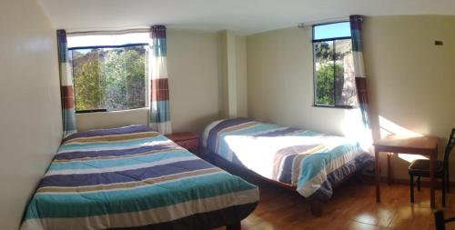 1 Schlafzimmer mit 2 Betten, einem Schreibtisch und 2 Fenstern in der Unterkunft Hotel El Gran Valletero in Cotahuasi