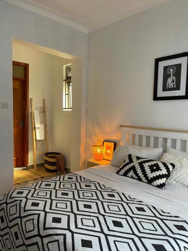 a bedroom with a bed with a black and white blanket at Charming two bedroom apartment in Bukoto Ntinda kampala in Kampala