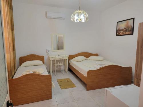 1 Schlafzimmer mit 2 Betten, einem Tisch und einem Kronleuchter in der Unterkunft Vila Islami in Durrës