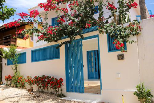 a house with blue doors and red flowers at Vila Marinella in Jericoacoara