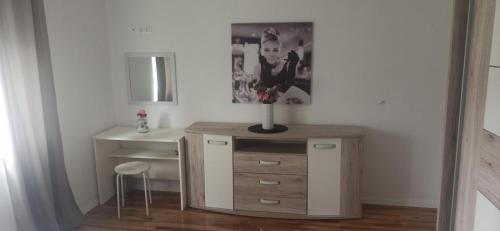 una habitación con escritorio y un jarrón de flores en una cómoda en Apartmani CARPE DIEM en Draškovec