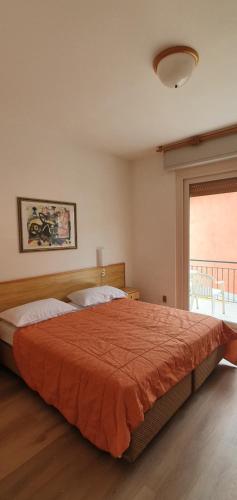 a bedroom with a large bed with an orange blanket at Malcesine rooms in Malcesine
