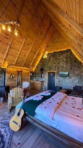 a bedroom with a large bed and a guitar at sitiela bungalov kir evi in Çamlıhemşin