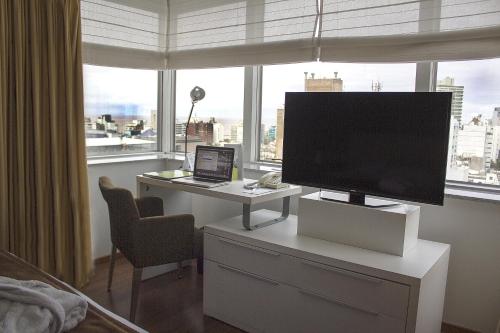 a bedroom with a desk with a television and a laptop at Regency Golf - Hotel Urbano in Montevideo