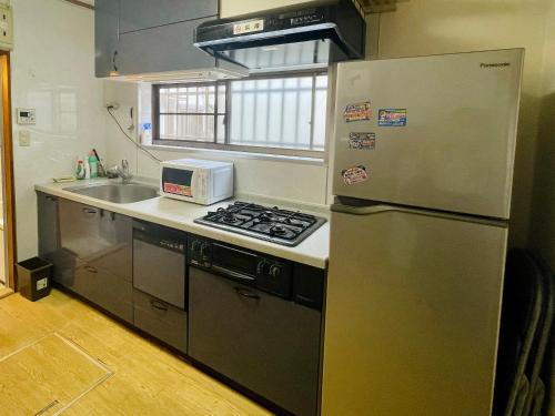 uma cozinha com um frigorífico de aço inoxidável e um lavatório em 池袋至近完全貸切一軒家 em Tóquio